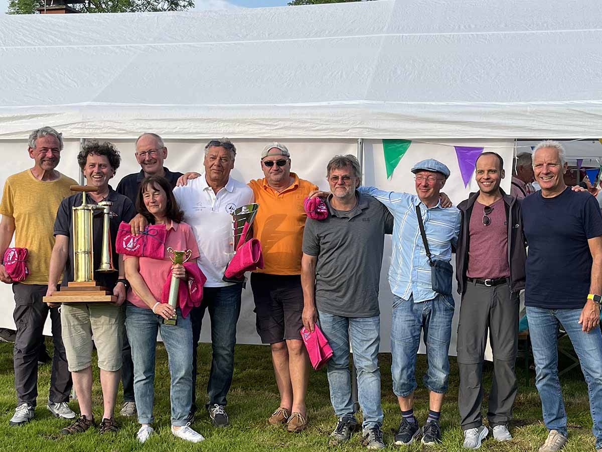 Zu sehen sind die Mitglieder, die bei der Regatta mitgesegelt sind. Alle lachen und halten stolz das Nebelhorn.